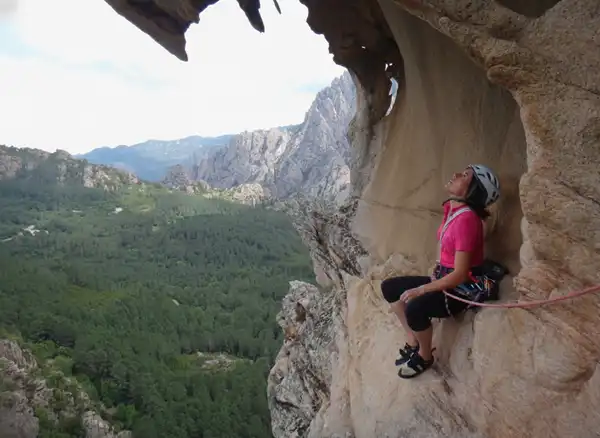 Escalade Corse - Grimpeuse au repos dans un tafonu, cavité typique du granit corse